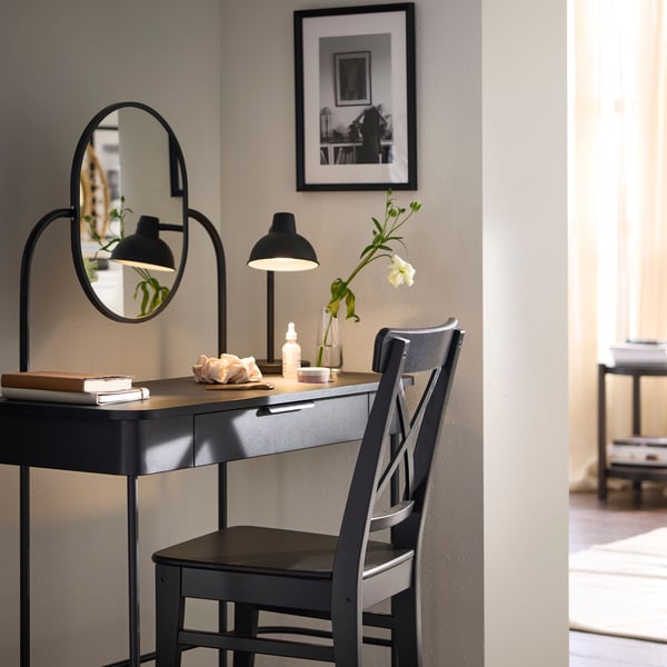 Coiffeuse GRÅFJÄLLET anthracite et chaise INGOLF en brun-noir devant elle, dans le coin d’une pièce.