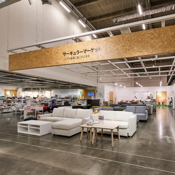 Various tables in different styles and colors displayed in a furniture store with lamps and accessories in the background.