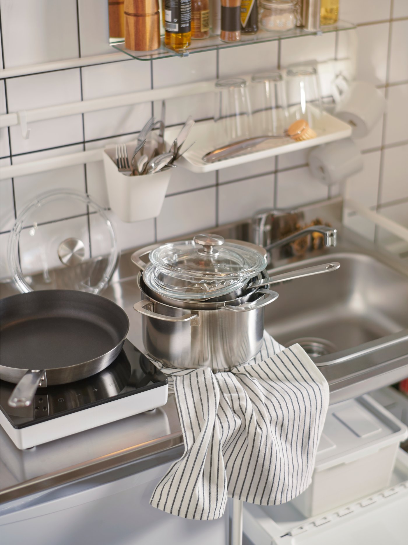 Una pequeña cocina con ollas y sartenes al lado del fregadero.