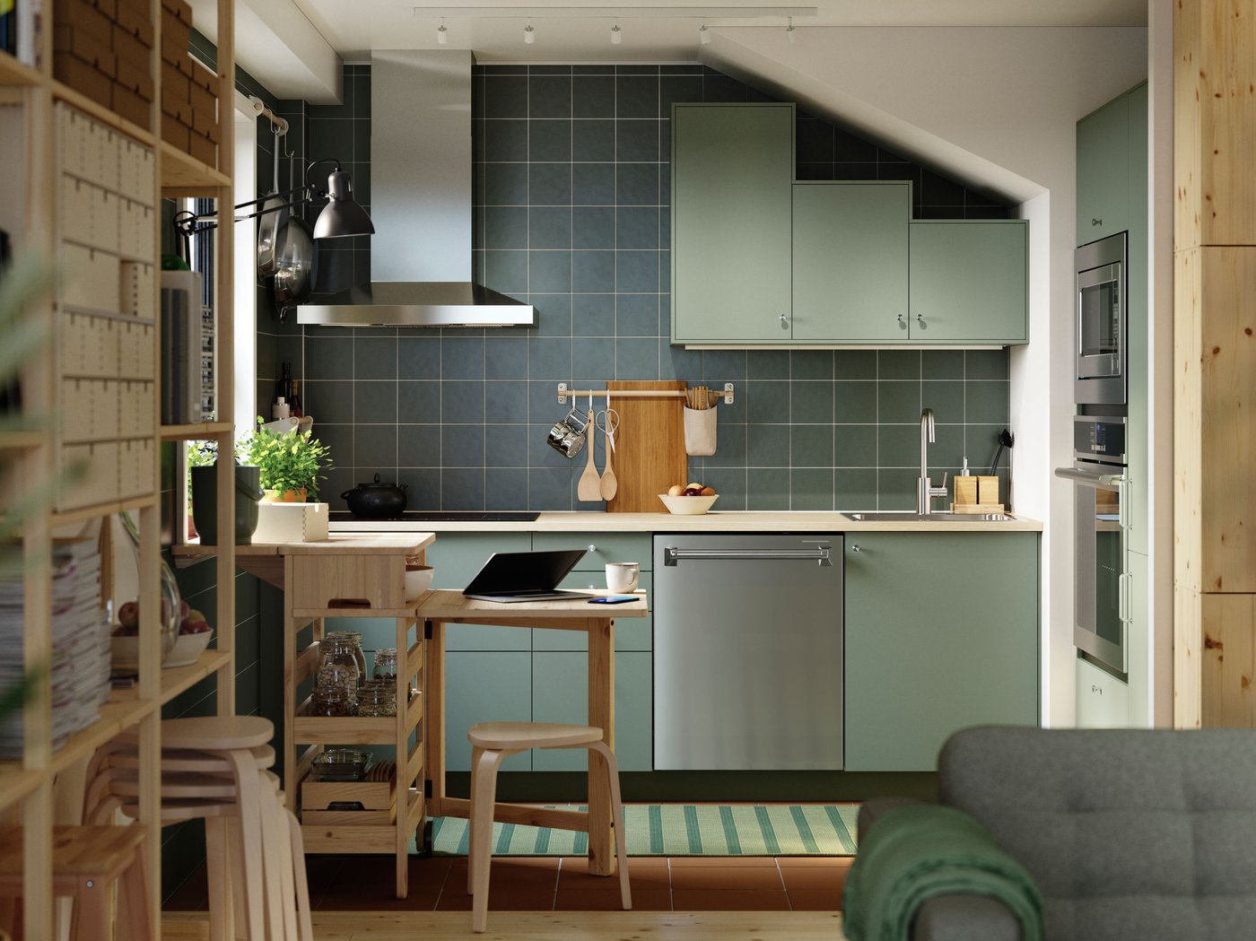 Cuisine verte en forme de L équipée de façades NICKEBO vert-gris, d’une table à abattants mobile RESARÖ avec rangement, et de quelques tabourets.