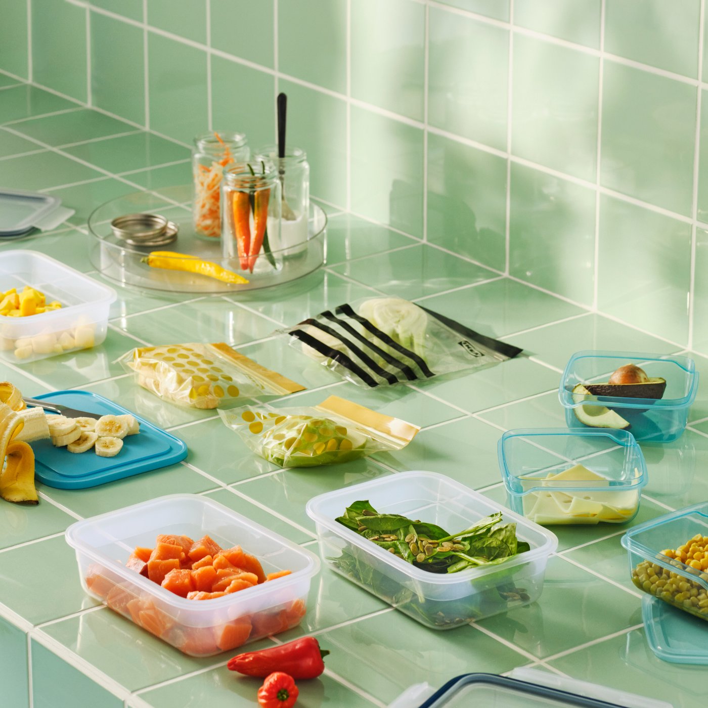 Eine geflieste Oberfläche mit IKEA Lebensmittelbehältern und wiederverschließbaren Beuteln mit verschiedenen Lebensmitteln, in einem Muster angeordnet.