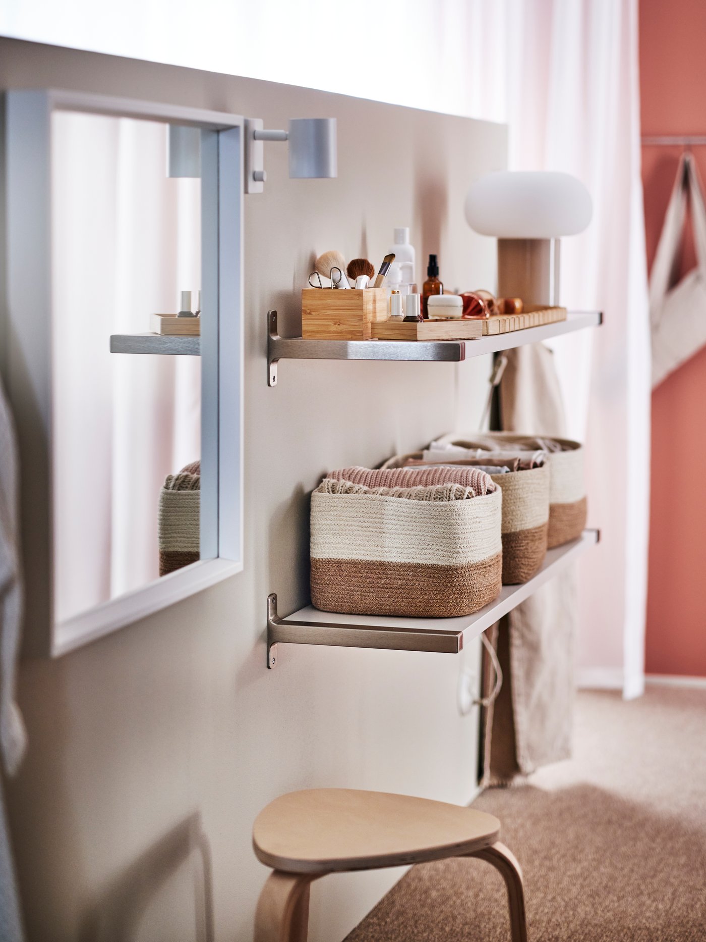 Un canasto LJUNGAN en un dormitorio sobre una repisa organizando artículos de belleza.