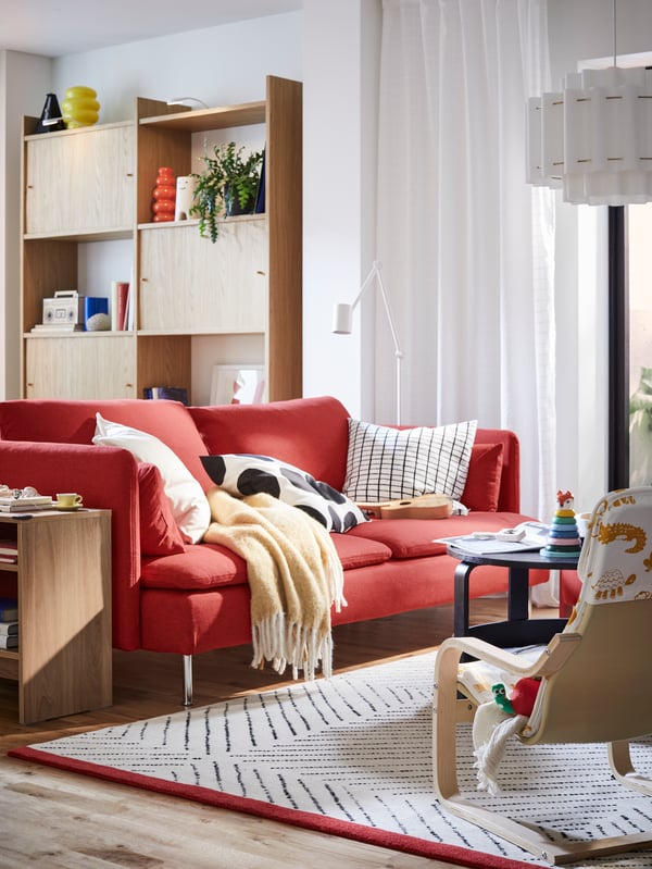 Crvena SÖDERHAMN sofa i HOLMERUD pomoćni stočić nalaze se u dnevnoj sobi nasuprot POÄNG dečje fotelje.