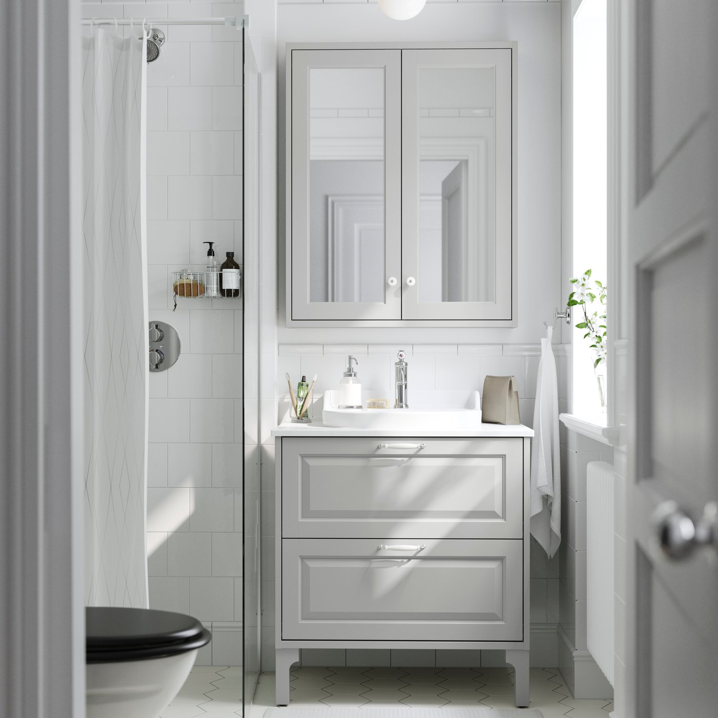 Bright bathroom with a gray vanity, mirrored cabinet and a shower with a white curtain.