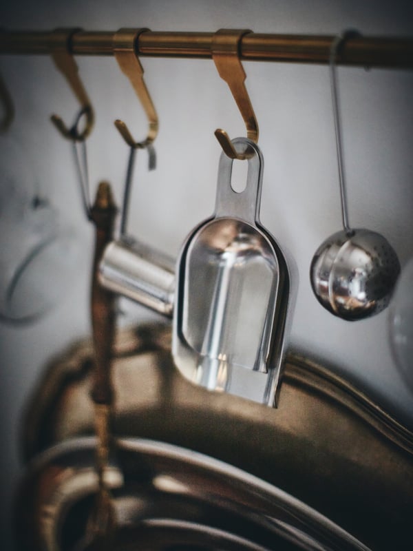 A close-up of a kitchen rail with stainless steel utensils hanging from it.