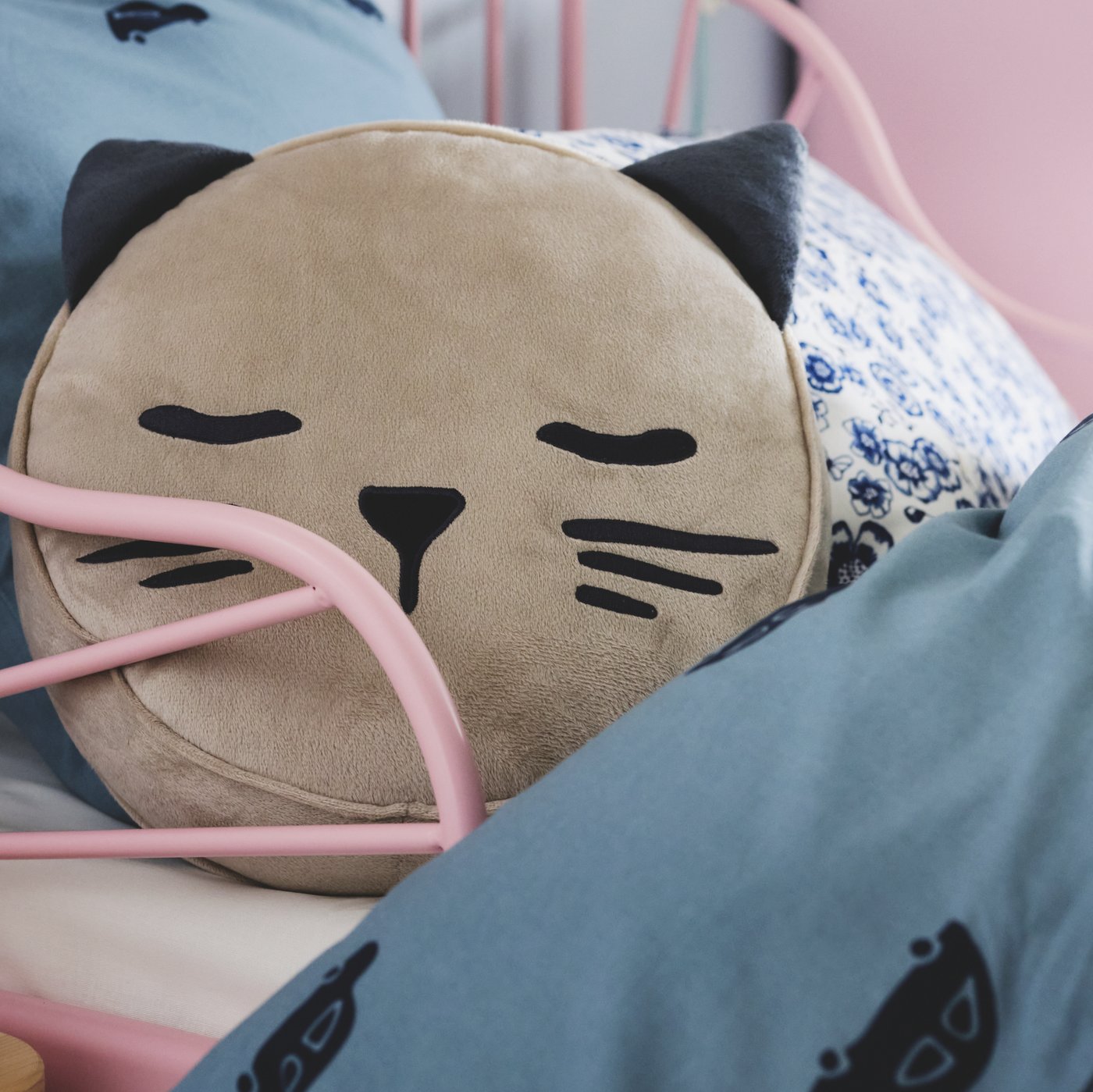 A beige BARNDRÖM cushion with pocket and a cat’s face and ears lies on a MINNEN extendable bed with BARNDRÖM bed linen.
