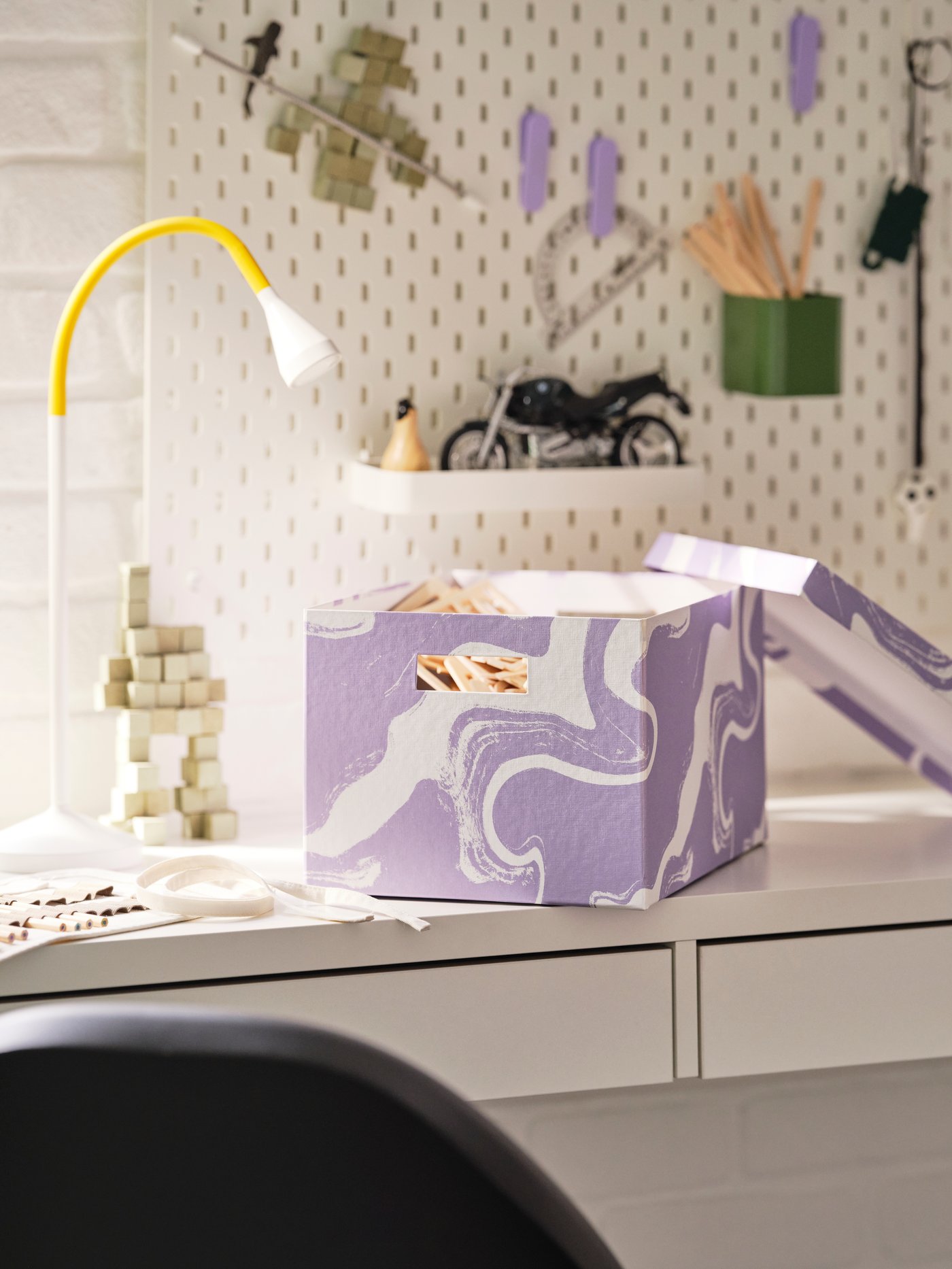 An IKEA TJENA purple storage box on a white desk