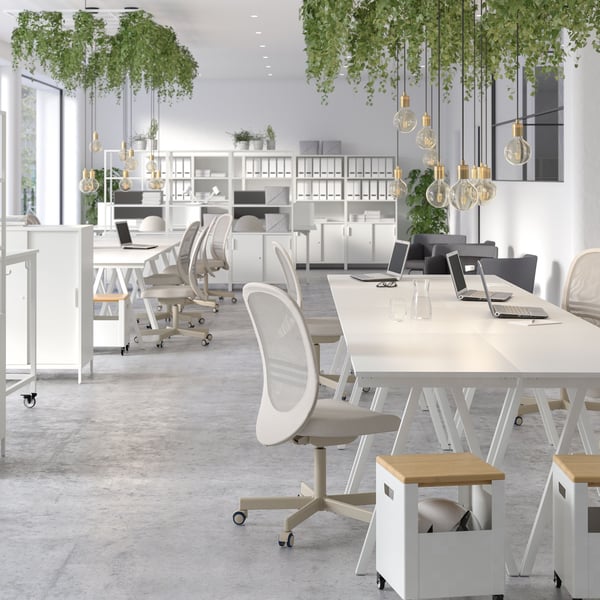 Several TROTTEN desks grouped together with a TROTTEN storage unit on castors in the front.