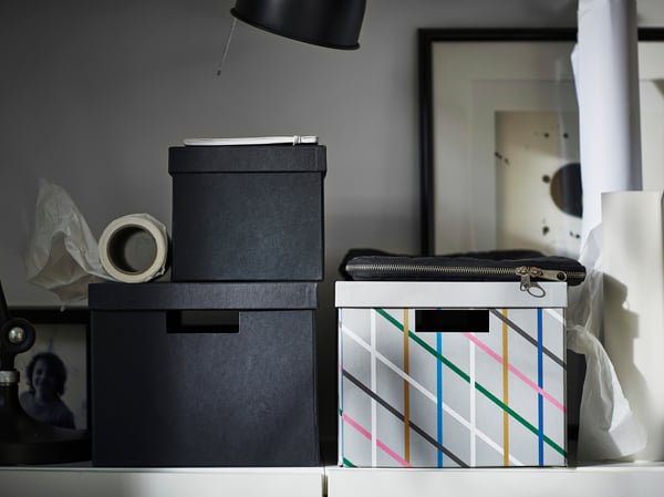 Una caja de almacenamiento TJENA gris multicolor/papel con tapa.
