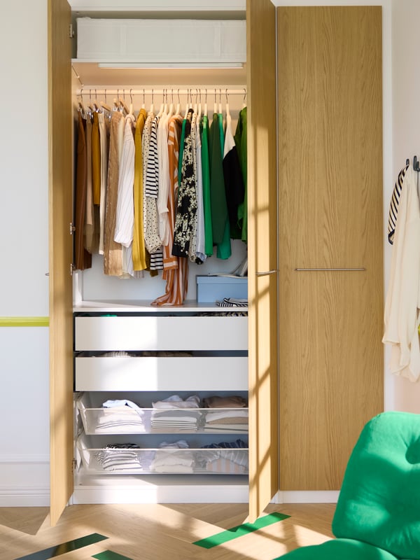 Close-up of PAX/STORKLINTA wardrobe combination, with two doors open to show clothes and stuff in perfect order.