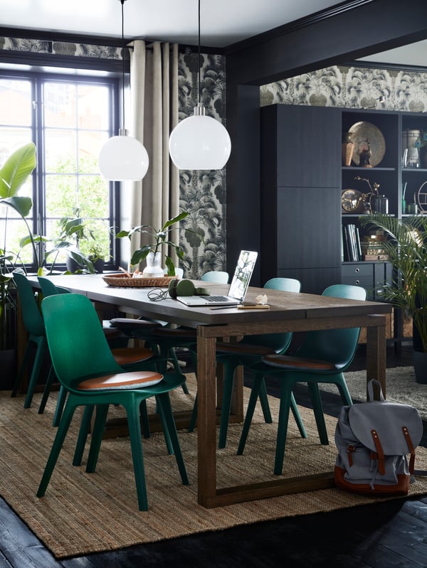 Six chaises ODGER vertes avec carreaux de chaise bruns autour d’une table MÖRBYLÅNGA avec deux suspensions au-dessus.