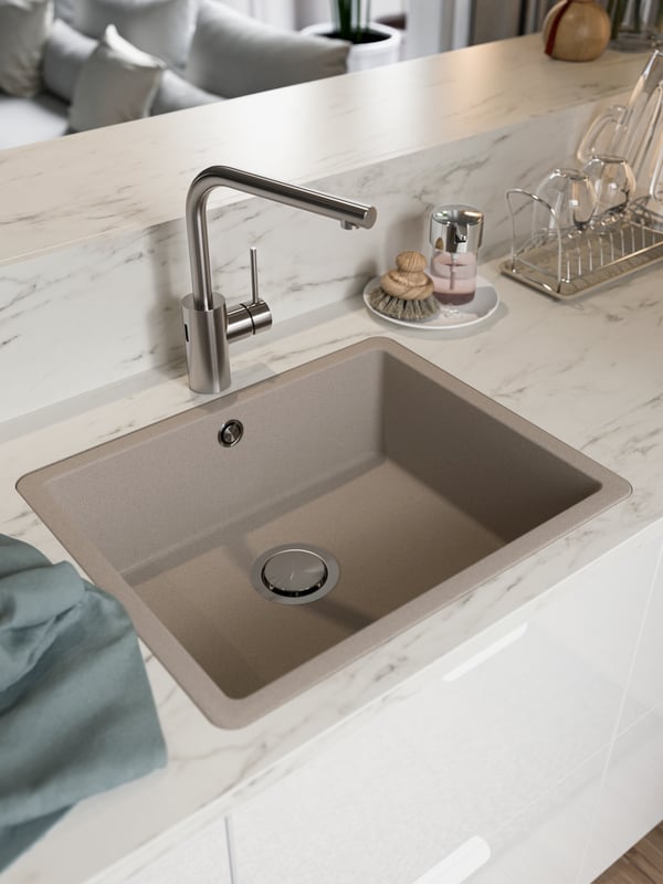 An inset sink, a kitchen mixer tap with sensor, a tea towel, wine glasses on a drying rack.