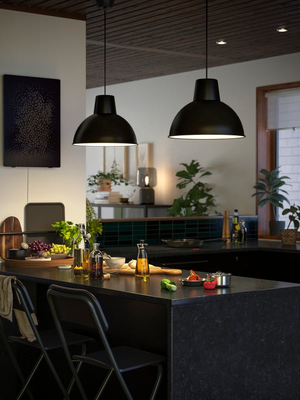 Two black SKURUP hanging pendant lamps are lighting up a kitchen island with a KASKER countertop in anthracite stone effect.