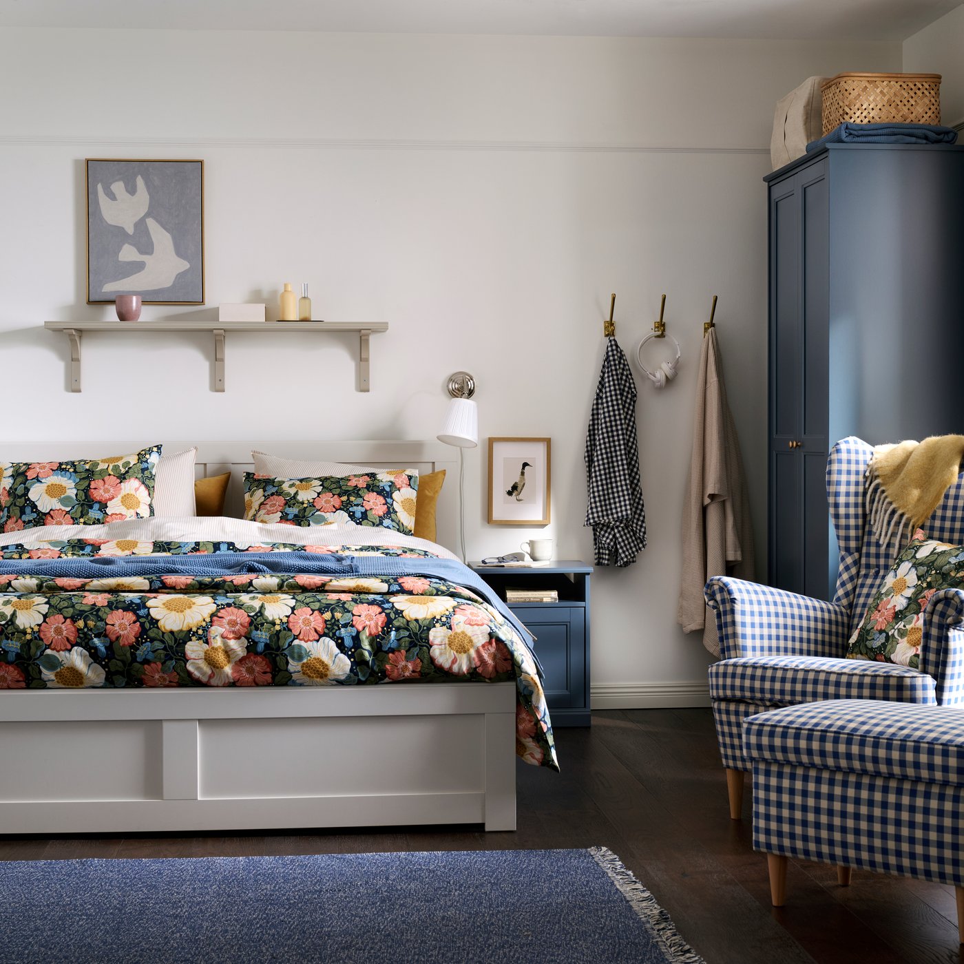 A traditional-style bedroom with a white FÅGELFJÄLLET bed, a blue FÅGELFJÄLLET bedside table and wardrobe, and floral bedding.