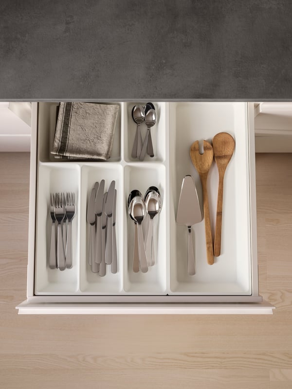 A kitchen drawer opened, revealing stainless steel cutlery in an UPPDATERA cutlery tray and utensils in a utensil tray.