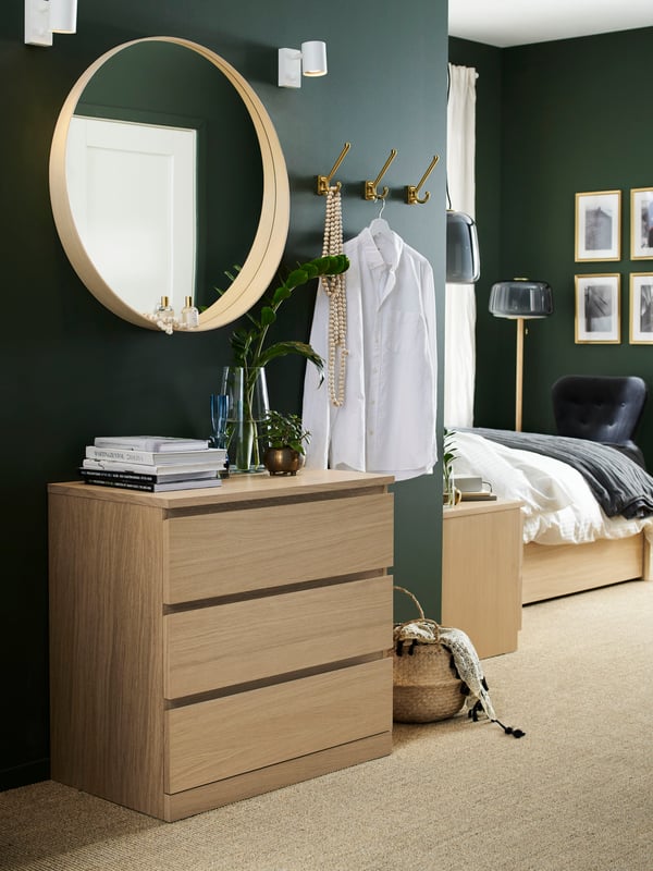 Cómoda MALM color madera en una habitación con cojines sobre un tapete.