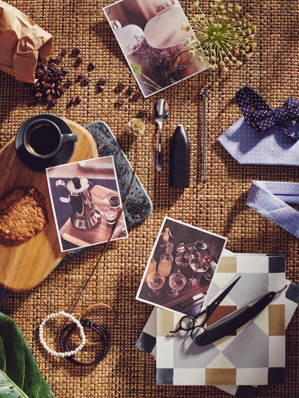 A hessian-covered surface holding a range of objects including coffee beans, a cup spoon, photographs and chopping board.