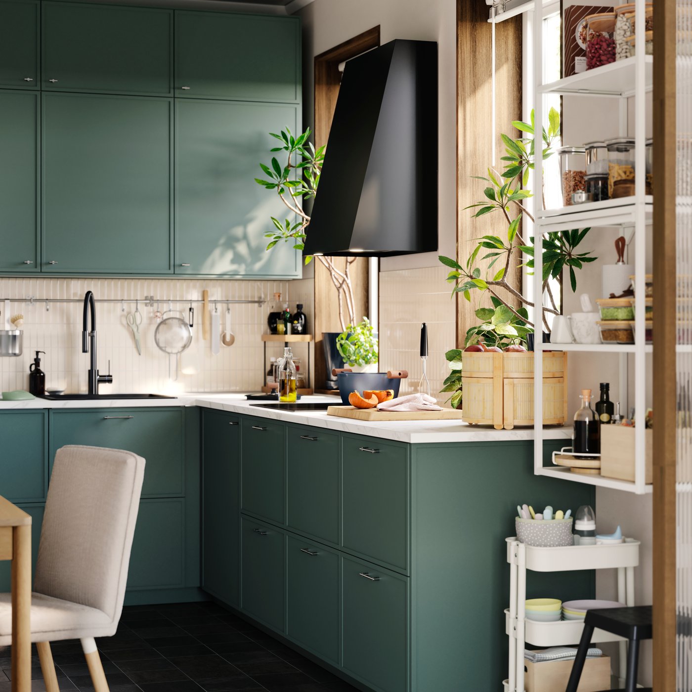 Petite cuisine avec plusieurs éléments bas et muraux aux façades ASPUDDEN gris-vert foncé et hotte aspirante à côté d’une fenêtre.