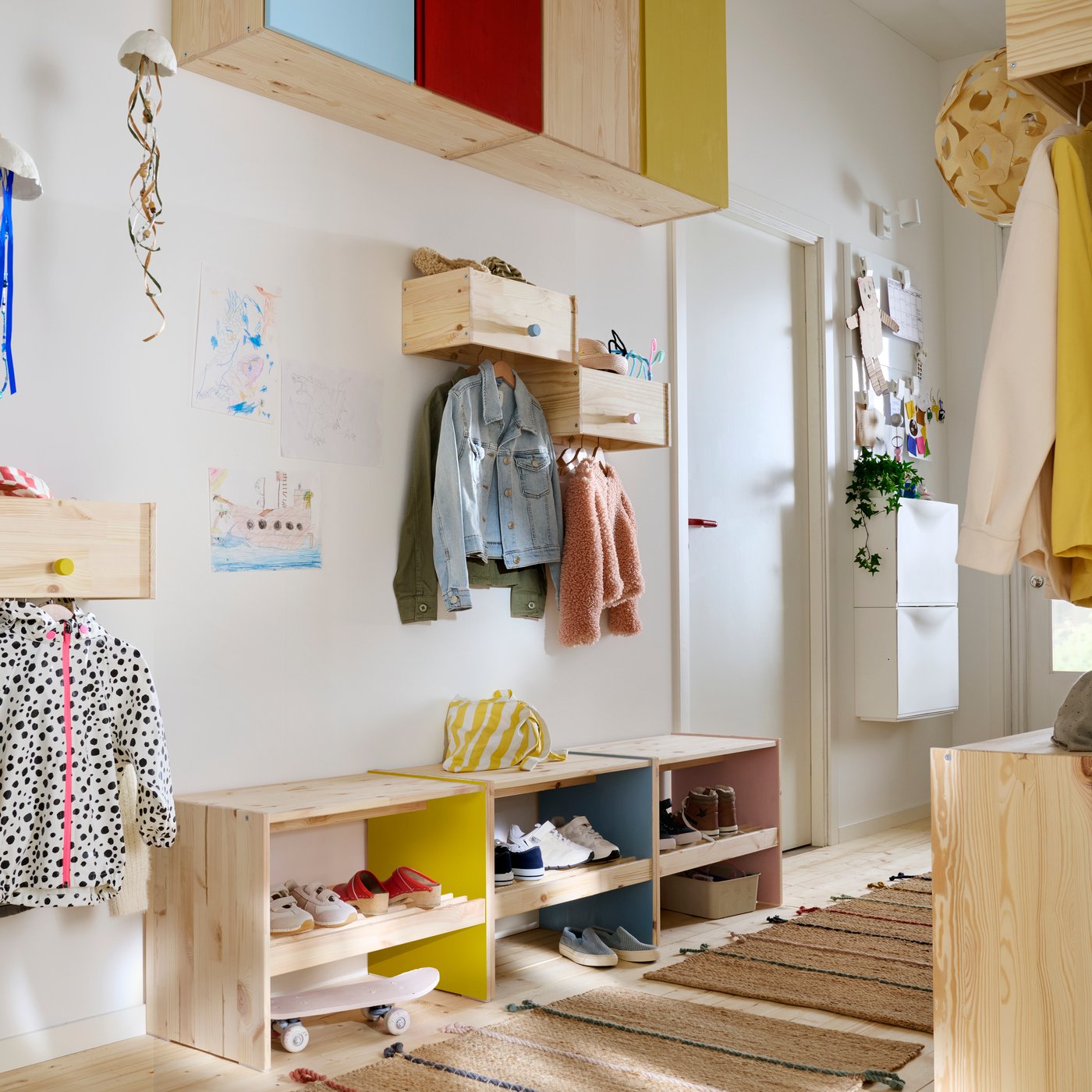 Un couloir familial doté de rangements RAGGBERG occupant toute la hauteur, le tout en pin naturel mais avec des détails peints dans des couleurs vives.