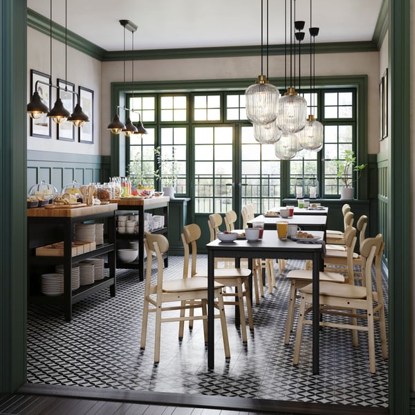 Ruimte in een café ingericht met TOMMARYD tafels, berken RÖNNINGE stoelen en twee VADHOLMA keukeneilanden en eetgerei.