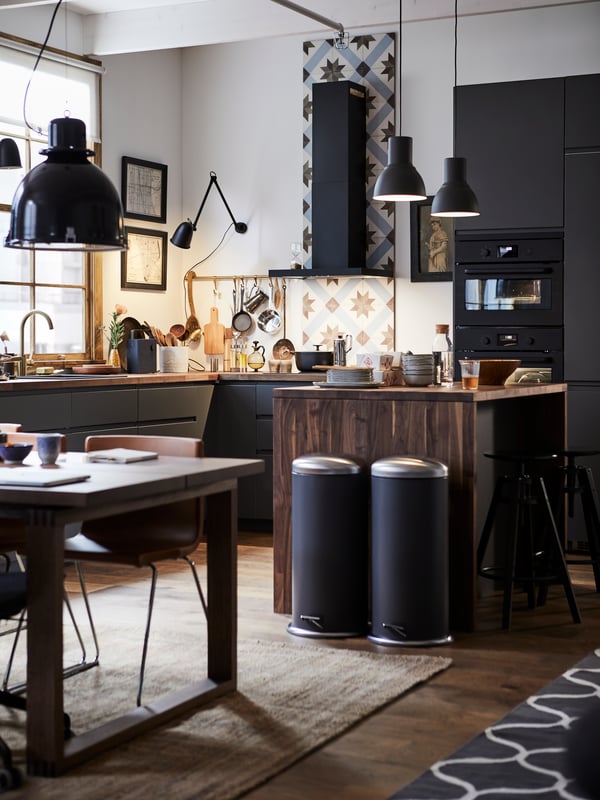 A SEKTION kitchen with a kitchen tile backsplash, wooden kitchen island and two MJÖSA pedal bins.
