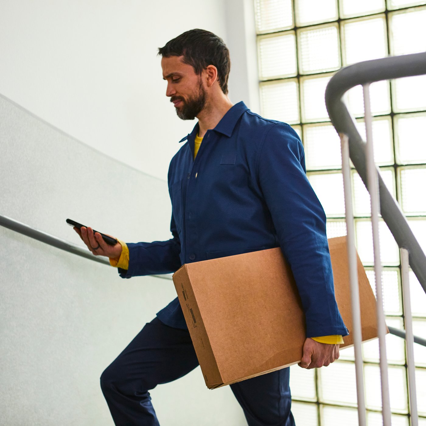 An IKEA co-worker climbs apartment block stairs holding a parcel
