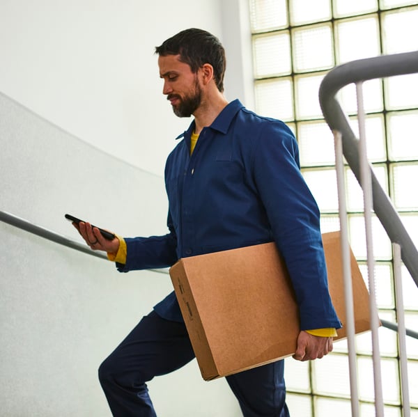 A man carries an IKEA box up stairs in an apartment block