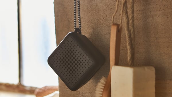 Crni VAPPEBY prenosni Bluetooth zvučnik visi na zidu kupatila.