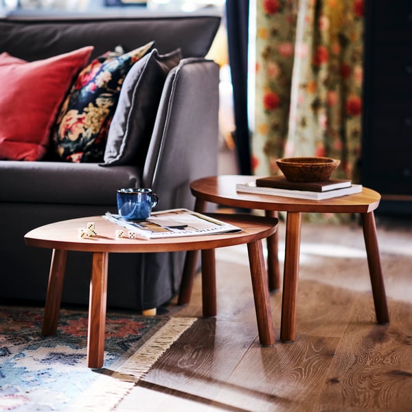 A cup and a small bowl on two STOCKHOLM nesting tables next to a grey BACKSÄLEN sofa.