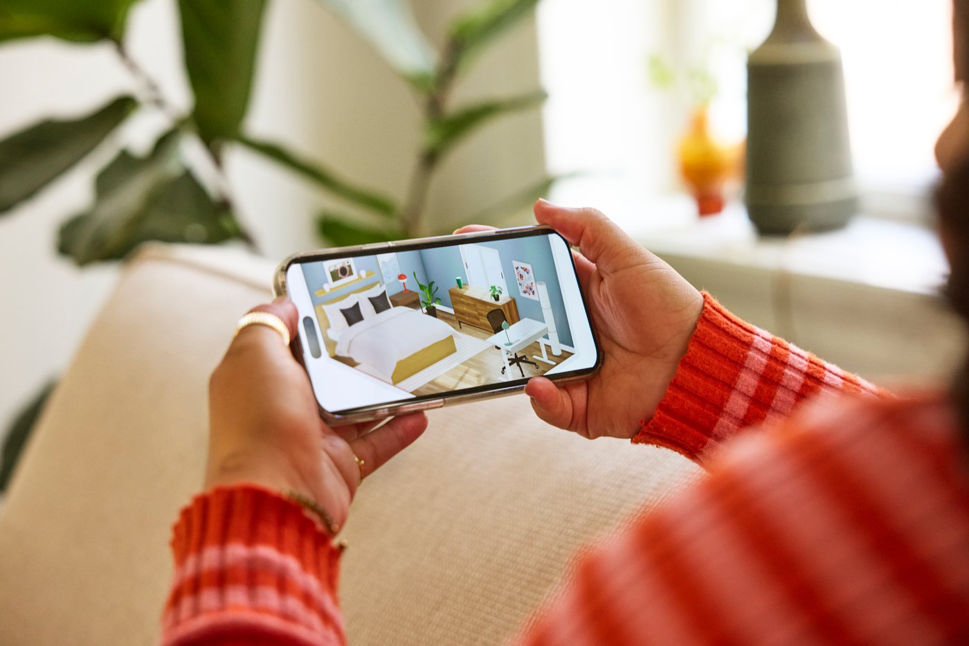 Someone is holding a smartphone in their hand, displaying a 3D plan from the IKEA Kreativ Planning Tool