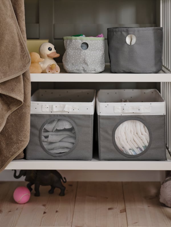A green/light grey LEN box set of 2 on a white changing table shelf, with two grey/dotted white LEN boxes on the shelf below.
