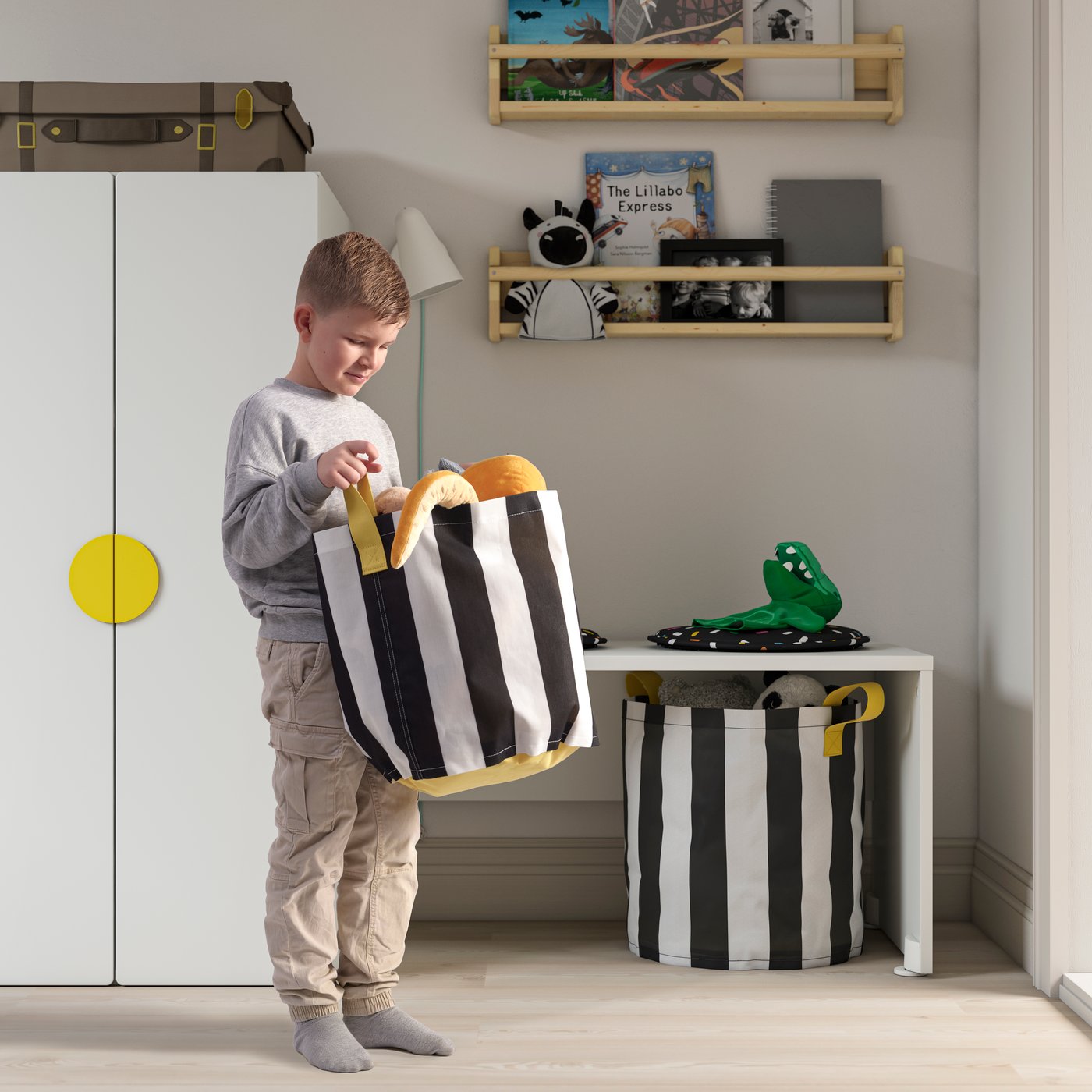 Boy picking up a basket full of organized toys