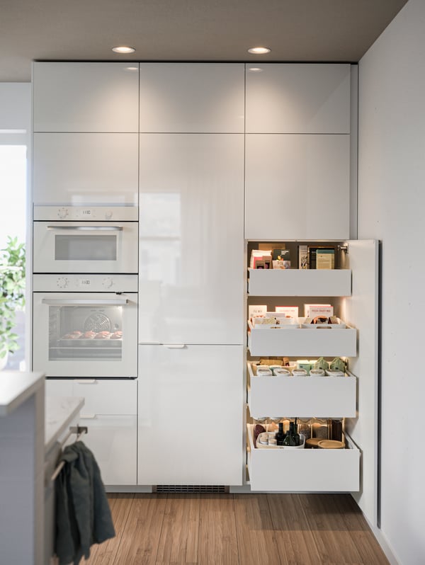 Kitchen cabinets and drawers with white fronts, drawers pulled open with food in boxes and containers.