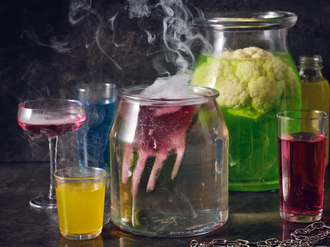 Colourful cocktails including a spooky punch made with DRYCK FLÄDER elderflower syrup and a red hand floating on top.