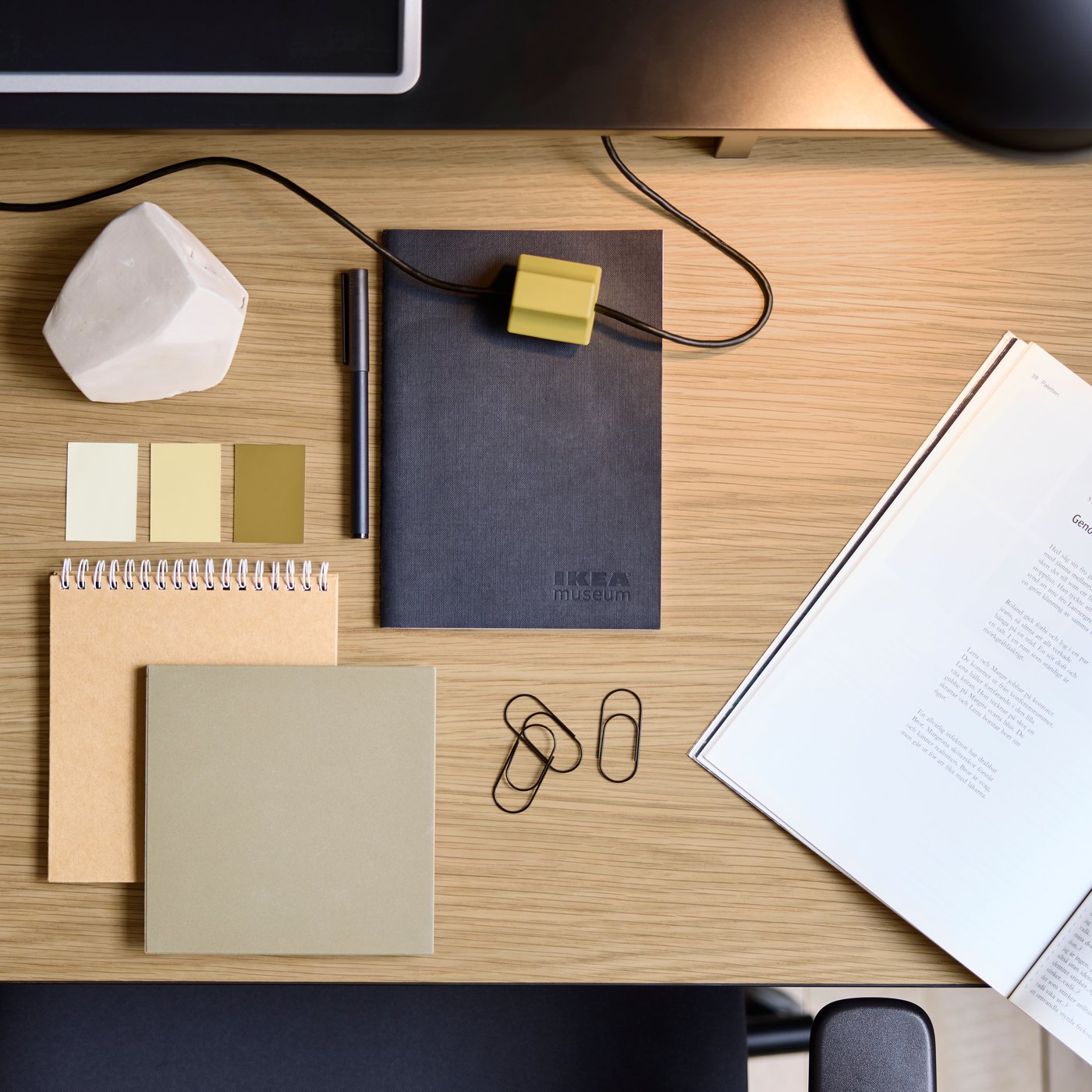 Bovenaanzicht van een MULLSJÖ bureau met een eiken werkblad waarop verschillende notitieboeken en paperclips liggen.