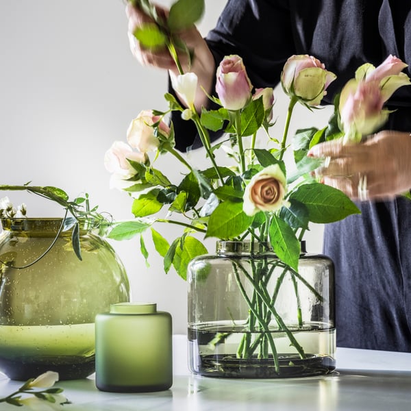 KONSTFULL green vases in different shapes placed on a table with roses in dusty pink inside.