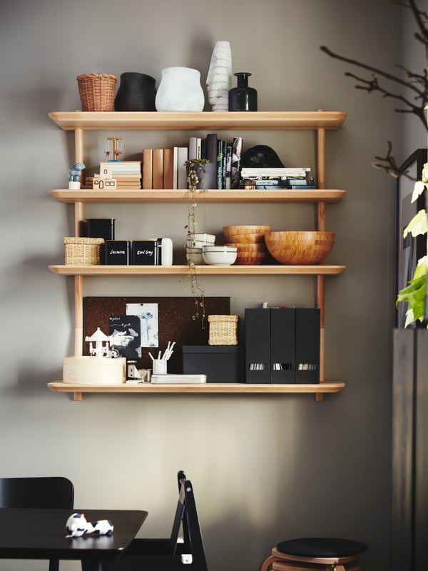 Bowls, magazine files, crockery and books are stored on four wall shelves in ash veneer that are wall-mounted by a table.