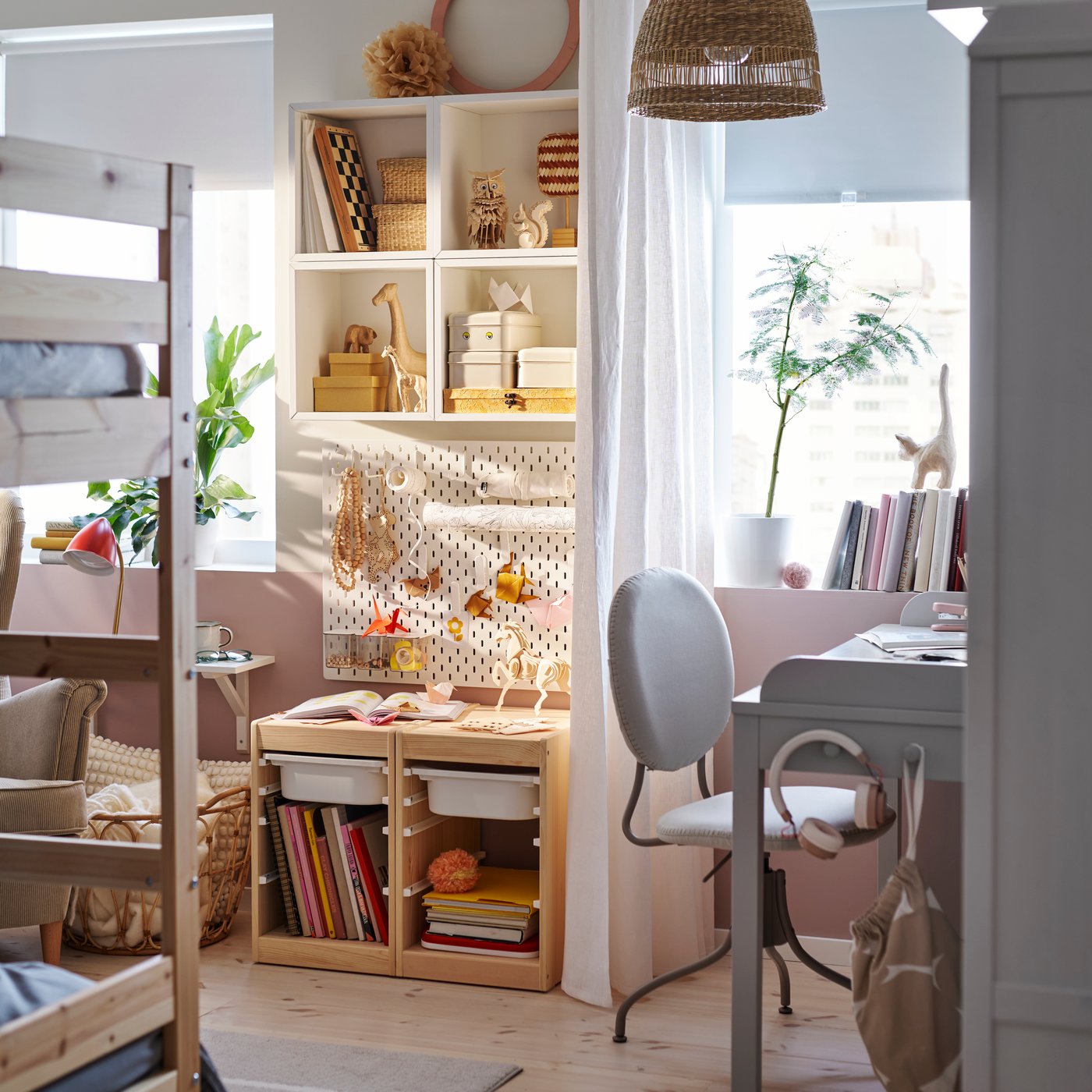 A cosy children’s bedroom with a grey SMYGA desk by a window with a white curtain behind it and a BJÖRKBERGET chair in front.