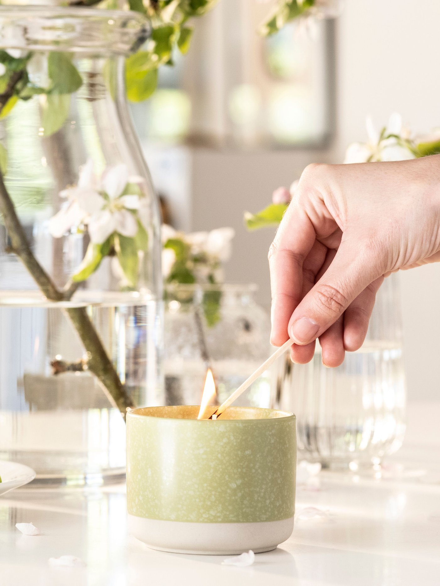An Apple/bright beige-yellow LÖVSKOGSLUND scented candle in ceramic jar