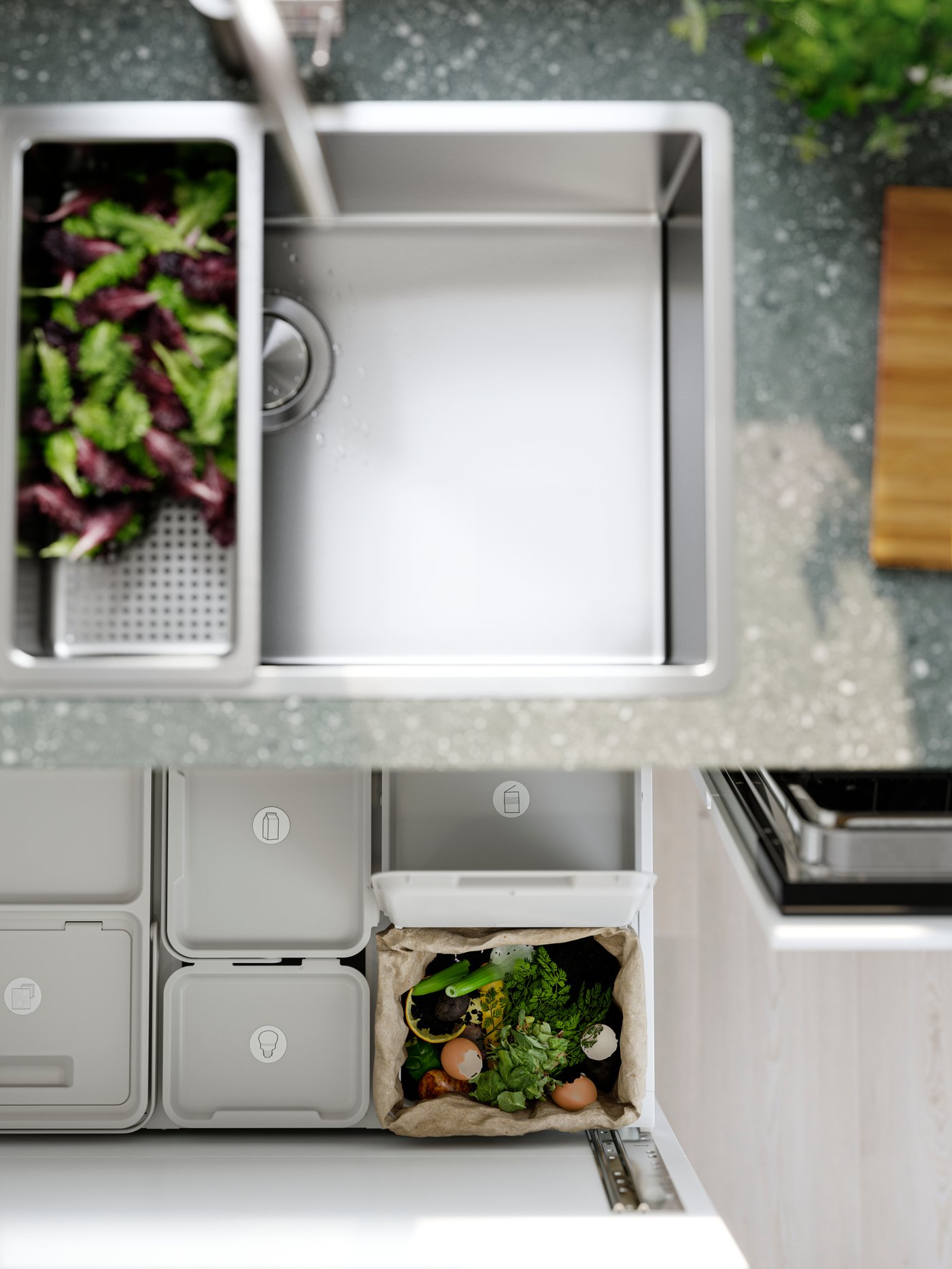 A VRESJÖN inset sink with one bowl has a colander with lettuce in it and waste sorting bins can be seen in the drawer below.