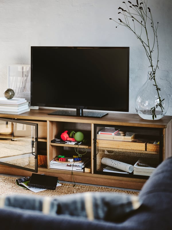 A wooden open LANESUND TV bench in a living room with a lot of personal stuff in it.