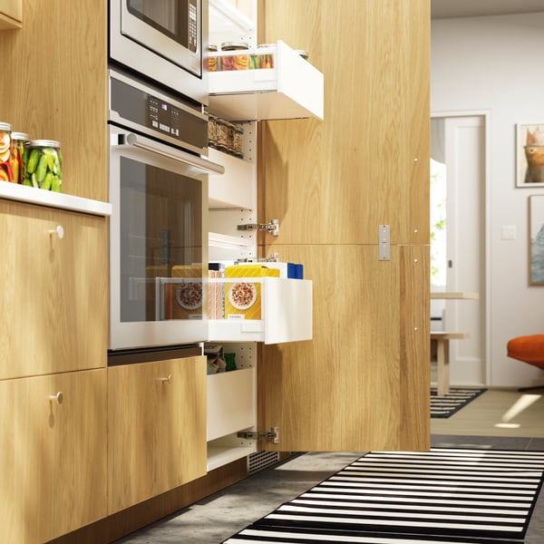 The door to a high cabinet is open and several MAXIMERA drawers are pulled out, revealing packages of food items inside.