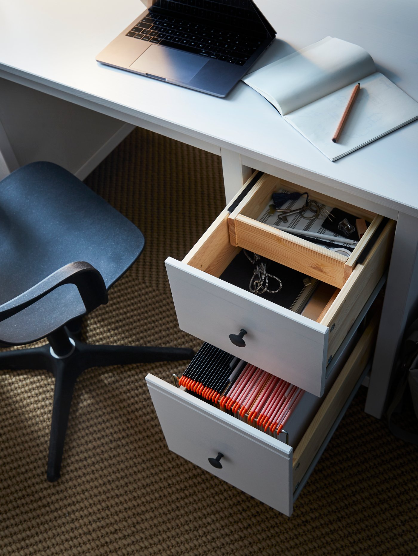 A HEMNES desk with drawers open, with compartmentalised folders, electronics and writing accessories.