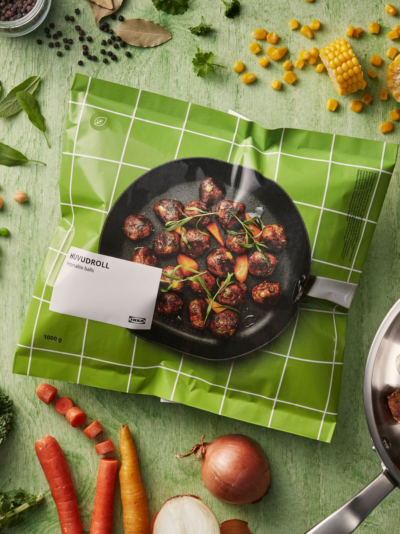 Verpackung der pflanzlichen HUVUDROLL Gemüsebällchen auf grünem Untergrund mit frischem Gemüse dekoriert.