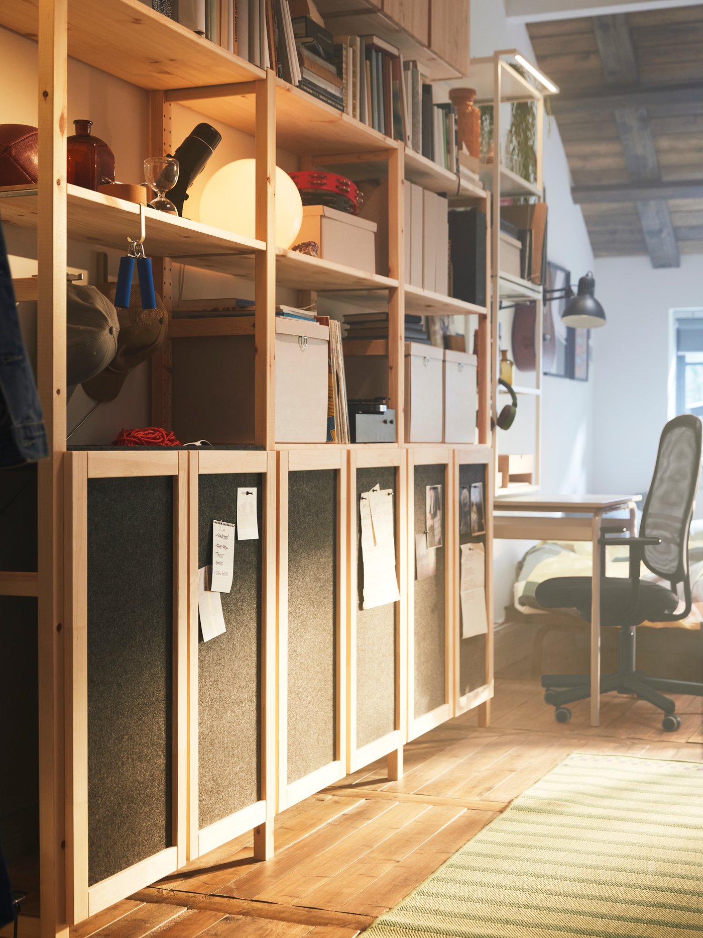 A large IVAR storage combination with a mix of closed cabinets with doors and open shelves with a round white lamp and books.