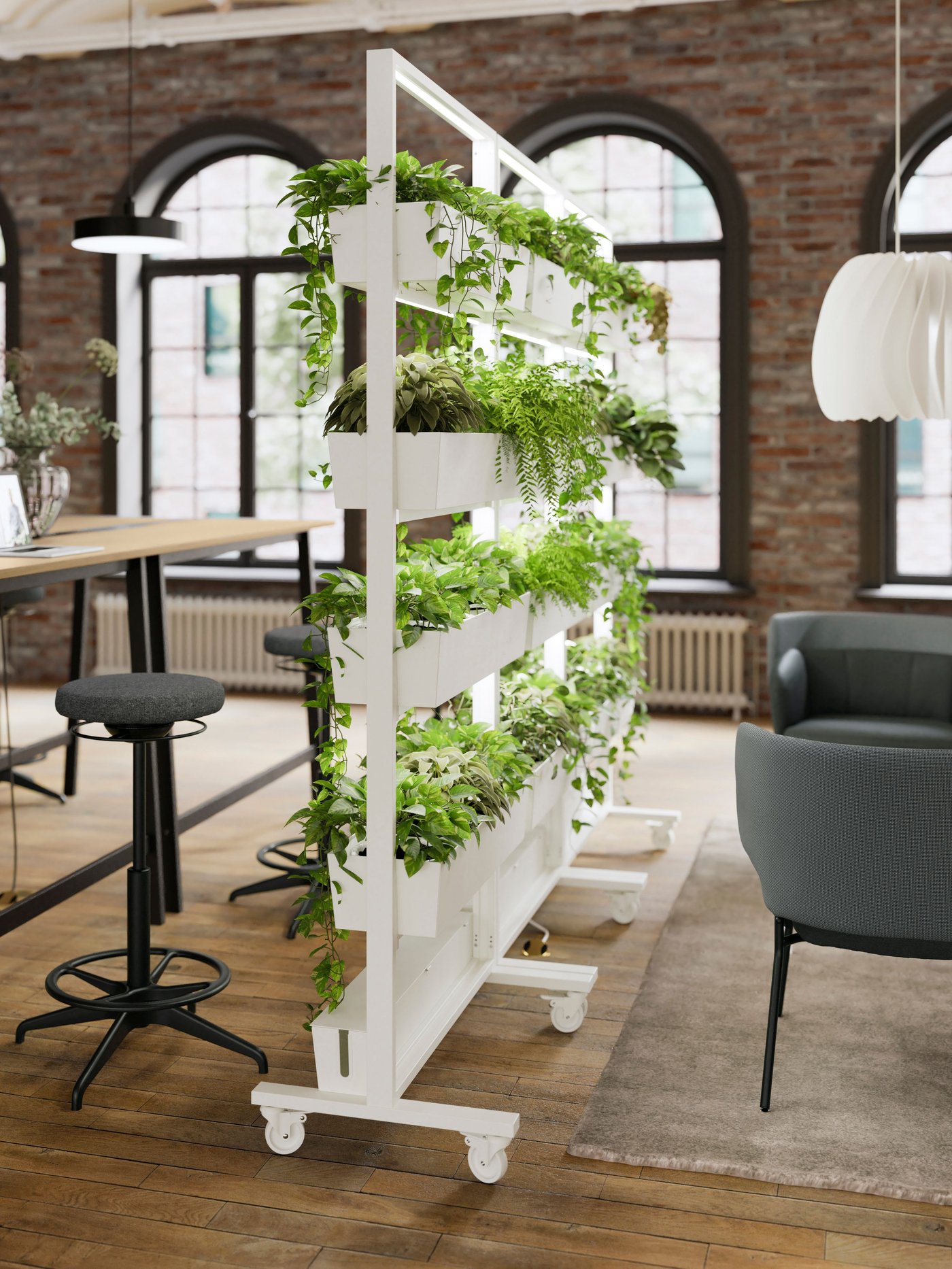 Un espace bureau de style industriel avec une structure à roulettes MITTZON garnie de plantes en pots, délimitant deux zones au sein de la pièce.
