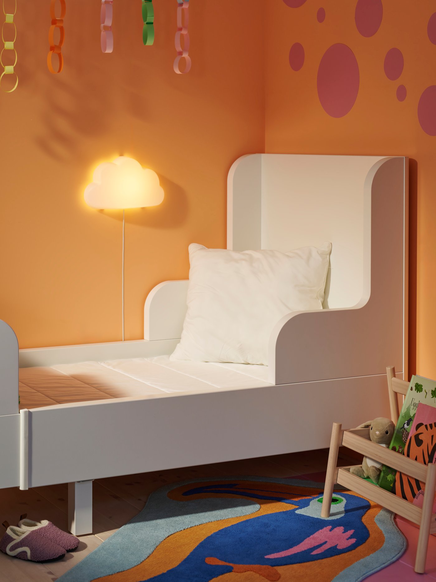 A white BUSUNGE extendable bed in an orange bedroom with a VIMSIG extendable mattress on it and an uncovered cushion pad.