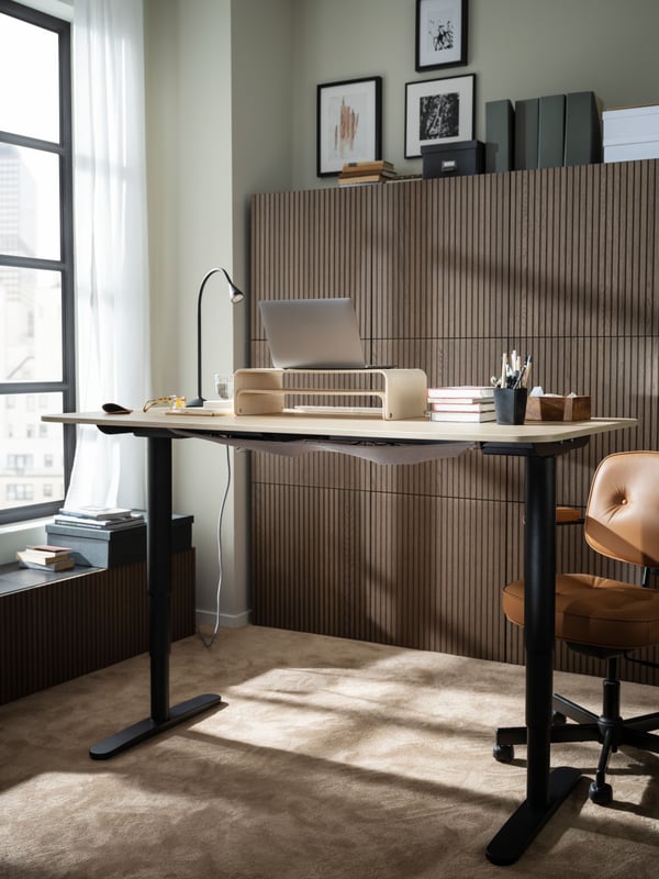 A workspace with a raised BEKANT sit-stand desk, an ALEFJÄLL office chair in front of a wall of wood-front BESTÅ cabinets.
