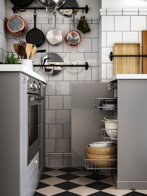 A base cabinet with the door open and mesh baskets drawn out next to a hob and oven in a kitchen with grey BODBYN fronts.
