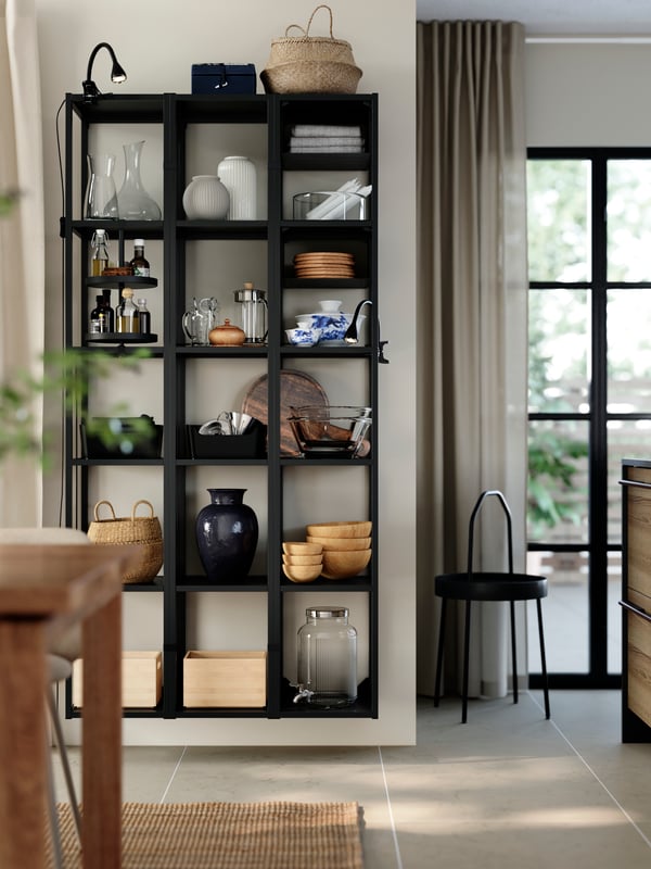 ENHET high frame wall shelves holding vases, and kitchenware, next to a window with curtains and a black countertop.